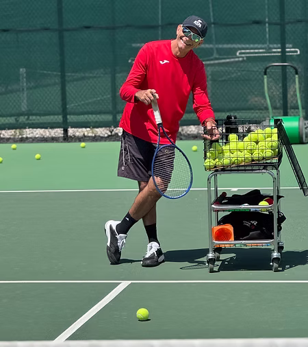 Mike Santomauro posing next to tennis ball stand
